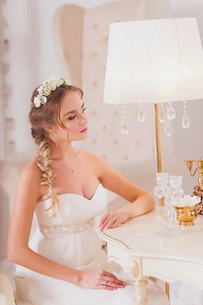 Vackra brud blond flicka i en bröllopsklänning bärs framför spegeln — Stockfoto
