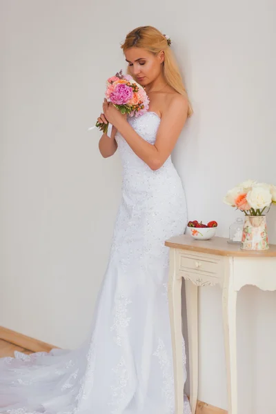 Retrato de uma bela noiva loira com buquê em uma luz interior, conceito de casamento — Fotografia de Stock