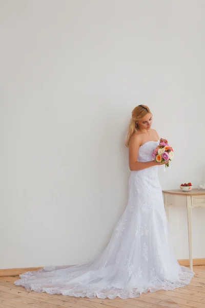 Retrato de uma bela noiva loira com buquê em uma luz interior, conceito de casamento — Fotografia de Stock