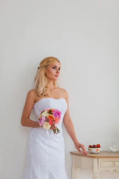 Retrato de uma bela noiva loira com buquê em uma luz interior, conceito de casamento — Fotografia de Stock