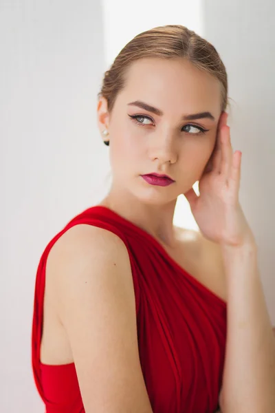 Jeune fille dans une robe rouge sur un fond blanc — Photo