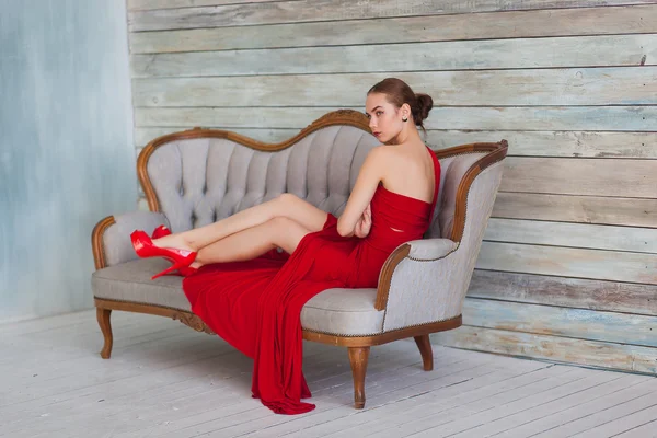 Lüks kadın kanepede Kırmızı elbiseli — Stok fotoğraf