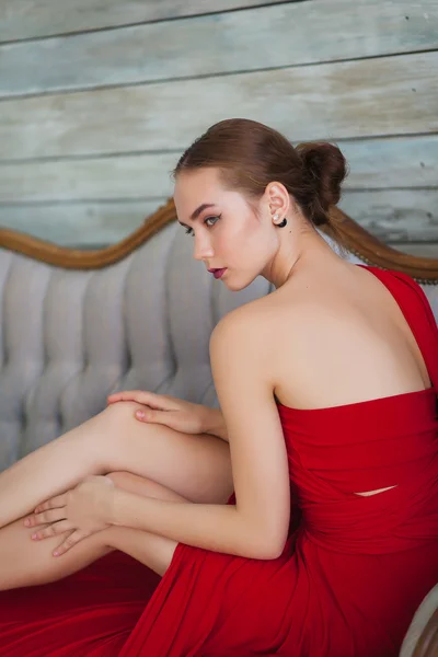 Luksusowa kobieta w czerwonej sukience na kanapie — Zdjęcie stockowe