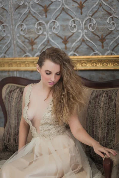 Kanepede oturan bej elbiseli güzel kıvırcık kız