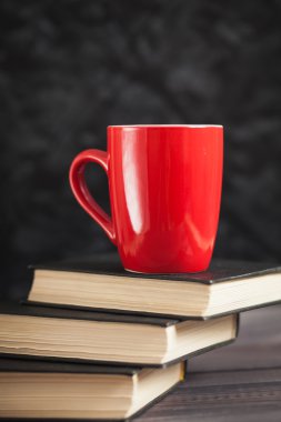 Kırmızı Kupası ve karanlık bir arka plan üzerinde siyah kitaplar