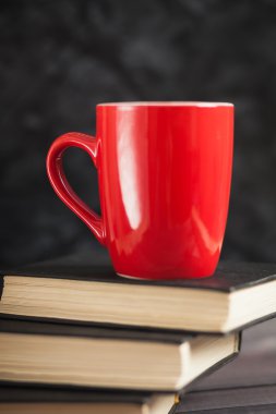 Kırmızı Kupası ve karanlık bir arka plan üzerinde siyah kitaplar