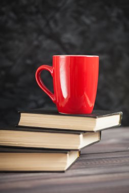 Kırmızı Kupası ve karanlık bir arka plan üzerinde siyah kitaplar