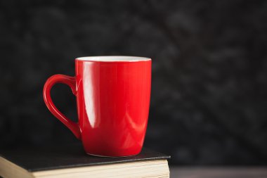 Kırmızı Kupası ve karanlık bir arka plan üzerinde siyah kitaplar