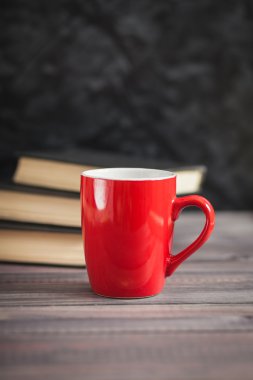 Kırmızı Kupası ve karanlık bir arka plan üzerinde siyah kitaplar