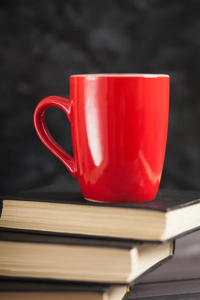 Kırmızı Kupası ve karanlık bir arka plan üzerinde siyah kitaplar