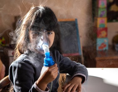 Girl doing the aerosol with the inhaler in her home. Respiratory system care concept