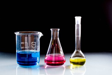 Koyu arkaplanda renkli sıvı bulunan laboratuvar için cam eşyalar