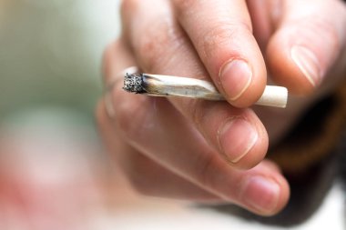 Sigarayı tutan erkeğin yakın plan görüntüsü.