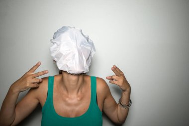 Beyaz arka planda genç bir kadın yüzünü gizliyor.