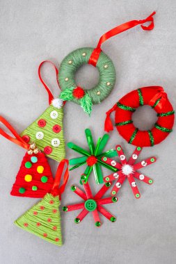 Collection of Christmas ornaments made from yarn and buttons. The ornaments include tree ornaments, yarn wreaths and popsicle stars
