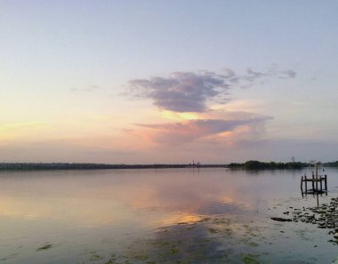 Ağaçlar, çimenler, gökyüzü ve güneşli ya da bulutlu gökyüzünün yansımasıyla kıyıdan gelen su manzarası