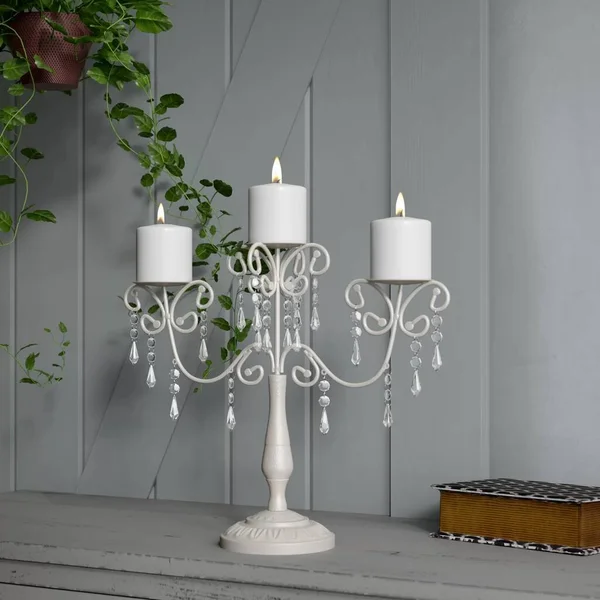 Beyaz ahşap arka planı olan, yanan üç mumlu zarif beyaz şamdan..