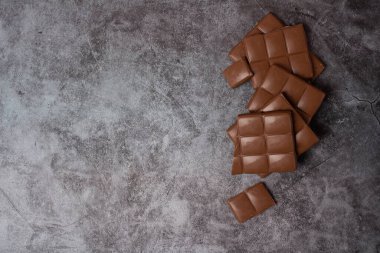 Gri arkaplanda sütlü çikolata parçaları ve Tex için boşluk