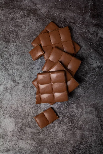 Gri arka planda süt çikolatası parçaları.