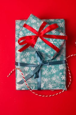 Kırmızı kurdeleli ambalaj kağıdında noel hediyeleri.