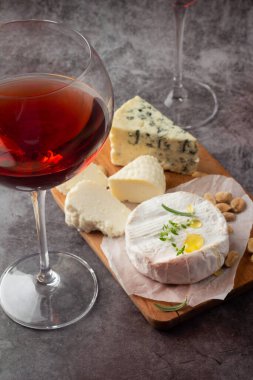 İki kadeh kırmızı şarap ve bir peynirli atıştırmalık.