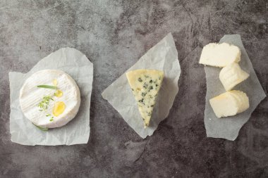 Gri bir sırt grubunda üç farklı peynir türü.