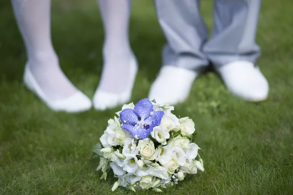 Wedding couple feet with flower bouquet.