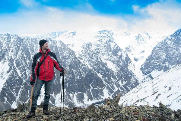 Hiker man on the summit with ice ax. Snowy mountain landscape. H