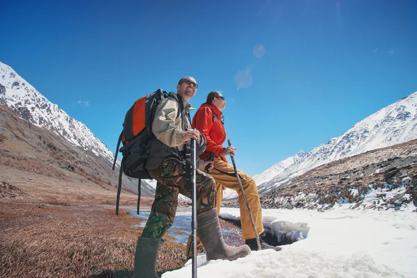 Feliz senderismo hombres en las altas montañas de nieve cerca de la montaña río helado —  Fotos de Stock