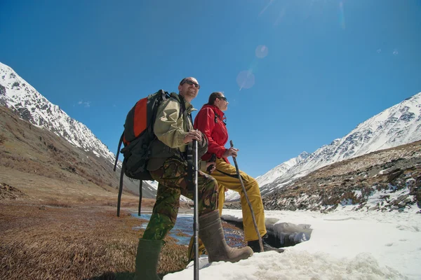 Feliz senderismo hombres en las altas montañas de nieve cerca de la montaña río helado —  Fotos de Stock