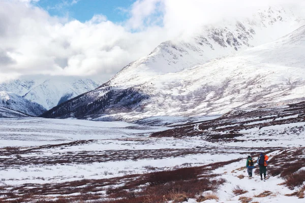 Dos mochileros van a las montañas nevadas en invierno. Viajes de invierno. Trekking de montaña. El hombre en armonía con la naturaleza. Invierno nevado paisaje de montaña. Dos viajeros en el camino nevado . —  Fotos de Stock