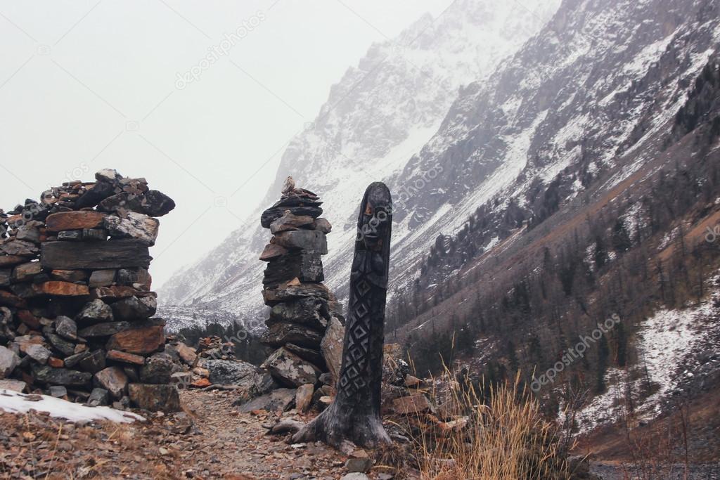 Winter mountain pass. Heathen pagan idol made from the wood. Gates made from stones.