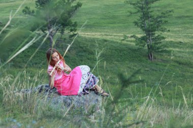 Çim sahada flüt genç Kızıl saçlı kadın oyun rahatlatıcı.