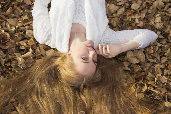 Meisje genieten van de zonnige herfstdagen op het verspreiden van gouden haren droog gras — Stockfoto