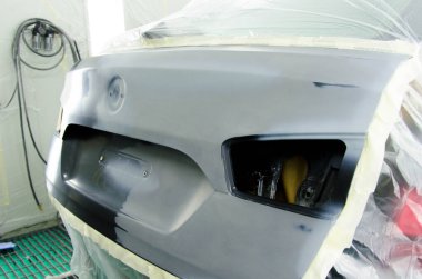 Araba boyası koruma folyosuyla kaplanmış lüks araba, profesyonel araç boyama kabininde sprey boyayla boyaya hazır ve sökülmüş. Araba Servisinde Araç Boyama İşlemi. Jpeg Resmi