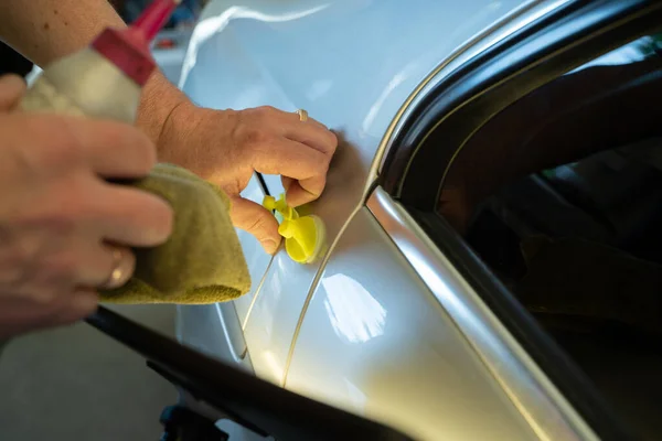 Prozess der farblosen Reparatur von Dellen an der Karosserie. Technikerhände mit Abzieher zur Befestigung der Delle am hinteren Kotflügel. pdr Umzugsschulung — Stockfoto