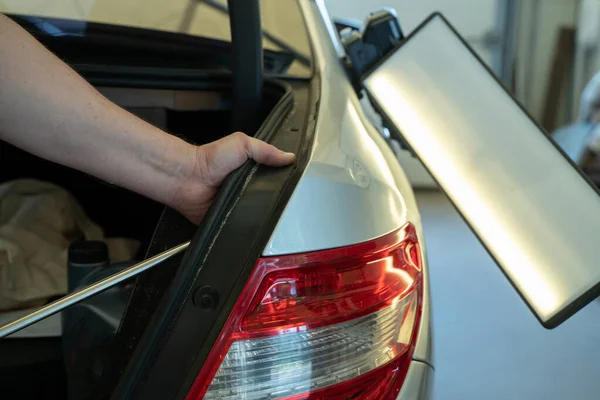 Prozess der farblosen Reparatur von Dellen an der Karosserie. Technikerhände mit Abzieher zur Befestigung der Delle am hinteren Kotflügel. pdr Umzugsschulung — Stockfoto