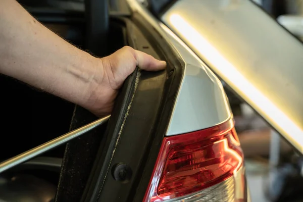 Prozess der farblosen Reparatur von Dellen an der Karosserie. Technikerhände mit Abzieher zur Befestigung der Delle am hinteren Kotflügel. pdr Umzugsschulung — Stockfoto