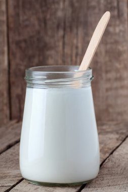 ahşap zemin üzerine kaşık ile cam kavanoza yoğurt
