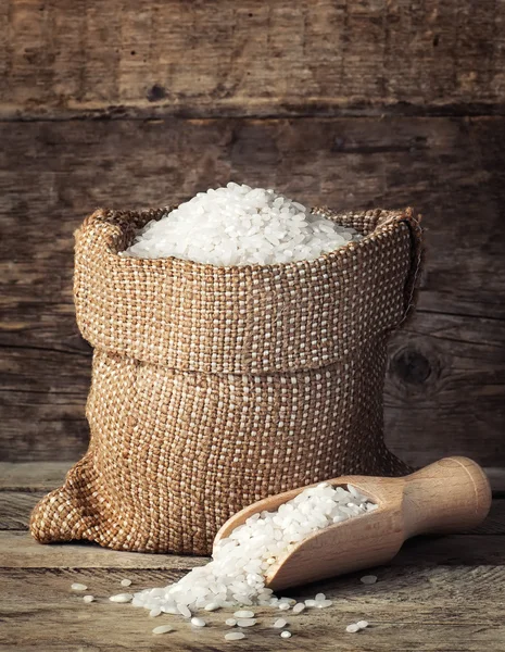 Riz en sac avec cuillère sur fond en bois — Photo