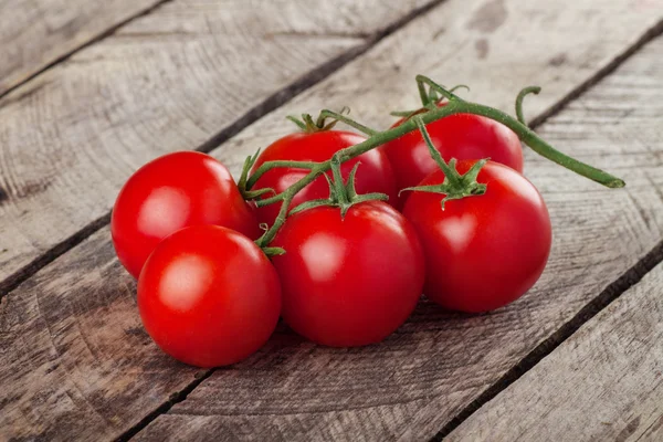 Ramo de tomates cereja no fundo de madeira — Fotografia de Stock