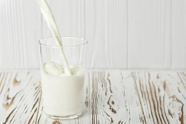 Milk pouring into glass — Stock Photo, Image