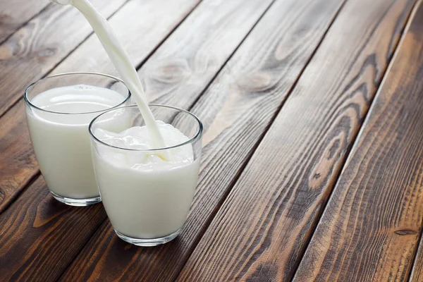 Milk pouring into glass — Stock Photo, Image