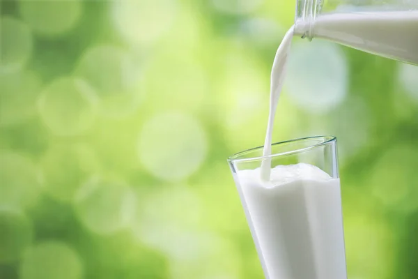 Milk pouring into glass — Stock Photo, Image
