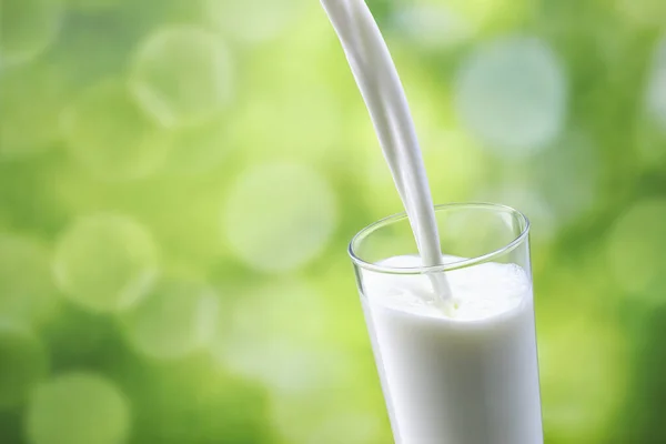 Milk pouring into glass — Stock Photo, Image