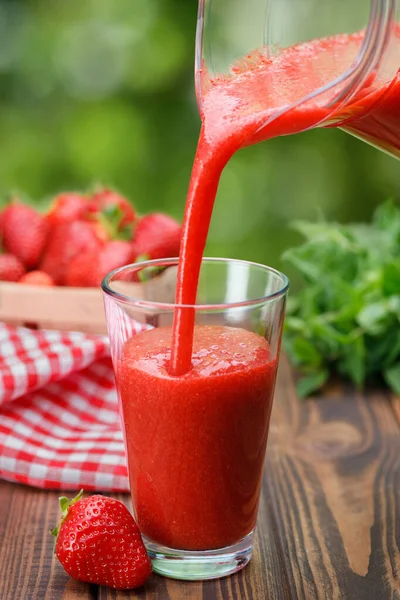 Çilekli smoothie testiden cama dökülüyor.