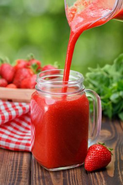 Çilek suyu kadehten cama dökülüyor.