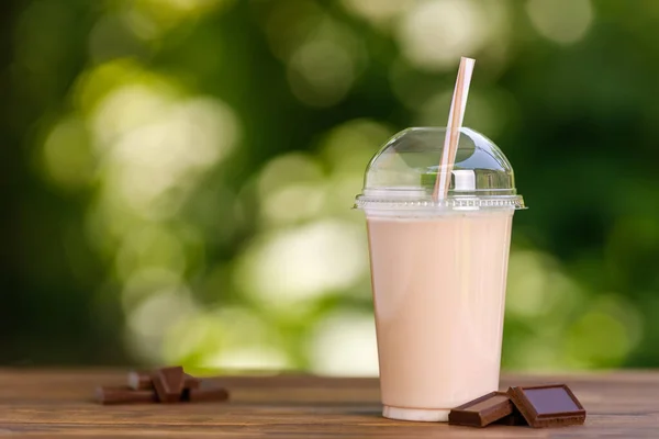 Milkshake au chocolat en verre plastique jetable sur table en bois — Photo