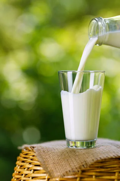 Milch aus Flasche ins Glas gießen — Stockfoto