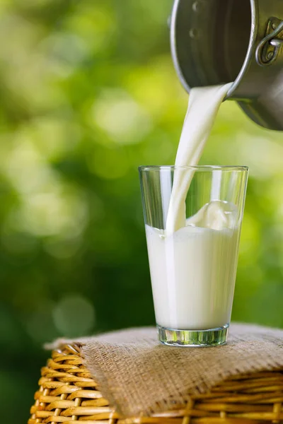 Mjölk häller från metall burk i glas — Stockfoto